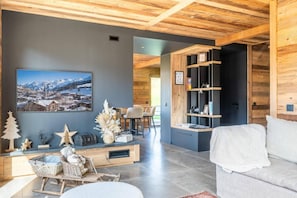 Una sala de estar moderna con un cuadro grande enmarco, estantes de madera y un rincón de descanso acogedor.
