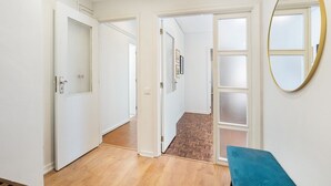 A hallway with white doors, a blue bench, and a mirror on the wall.