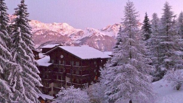 A lodge with a wooden exterior and snow-covered roof, surrounded by snow-laden trees and mountains in the background. - 200m from ski slopes, Ground floor, terrace, balcony, tv, ski locker, 45m², Valfréjus (Valfréjus)