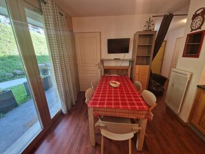 A dining area with a red checkered tablecloth, wooden chairs, a television on the wall, and a window with curtains. - 200m from resort center, Ground floor, terrace, balcony, tv, ski locker, 45m², Valfréjus (Valfréjus)