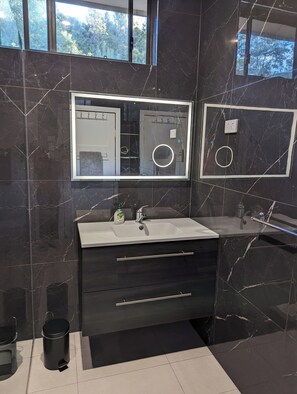 Ein modernes Badezimmer mit einem großen Spiegel, einem Waschbecken und einem Waschtisch.