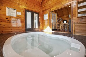A wooden cabin interior with a spa area, including a hot tub and wooden furniture.