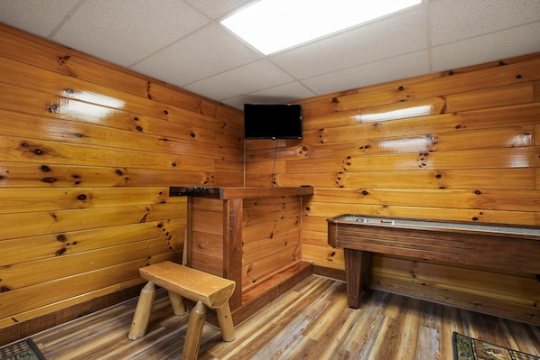 A wooden cabin with a bench, a fireplace, and a television mounted on the wall.