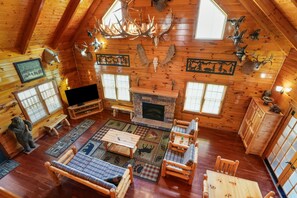 A log cabin interior with a fireplace, wooden furniture, and deer antlers on the walls.