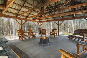 A covered outdoor seating area with wooden benches and a central fire pit.