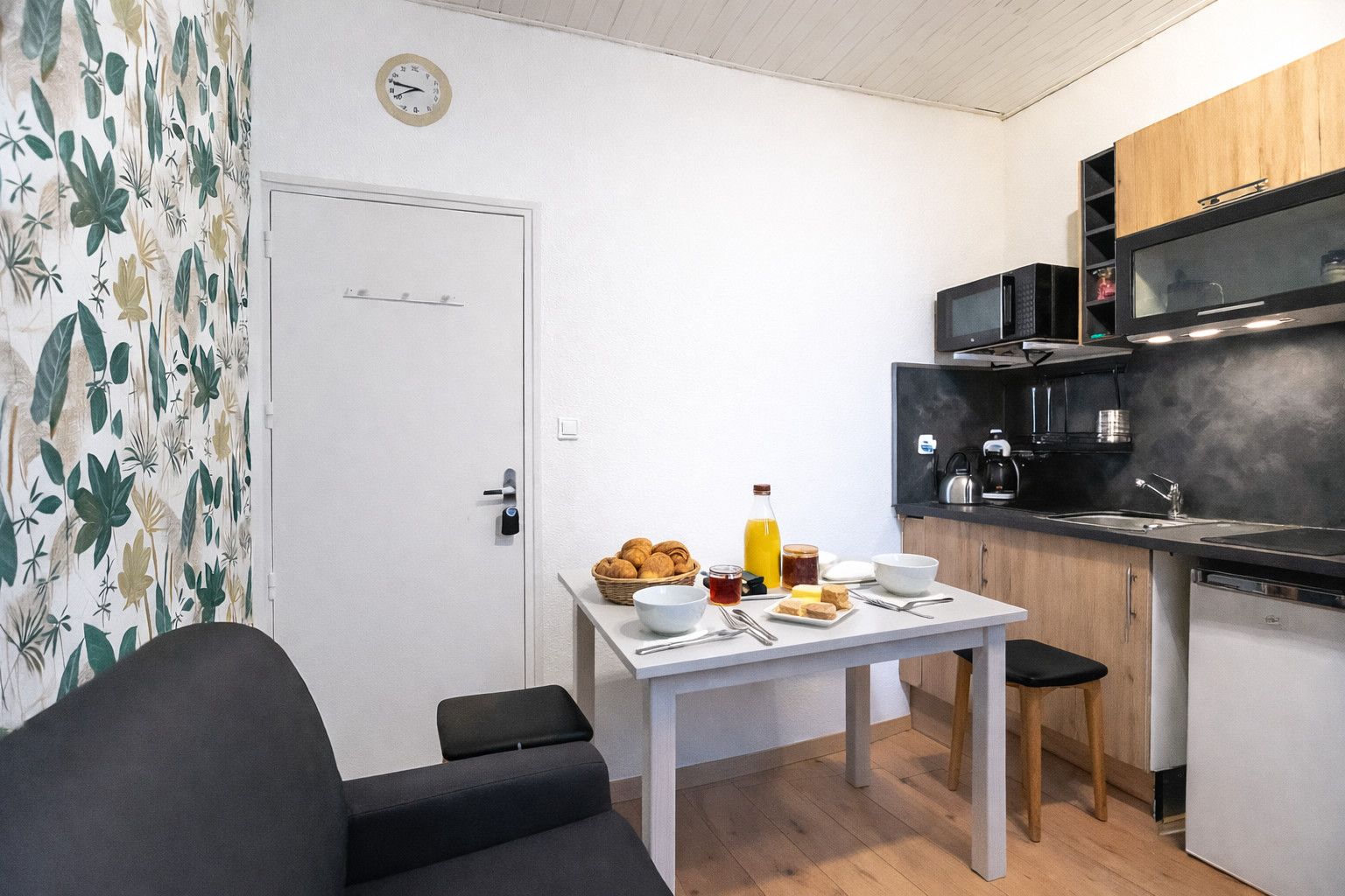 A compact kitchen with a dining table set, a microwave, and a refrigerator.