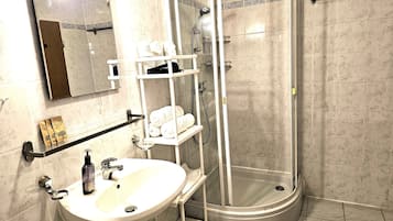 Une salle de bain équipée d’un lavabo, d’un miroir, d’un porte-serviettes et d’une douche à parois de verre.