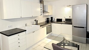 A modern kitchen with white cabinetry, a stainless steel refrigerator, a microwave, and a coffee maker. - Apartmenthaus - Mackenbach (Mackenbach)