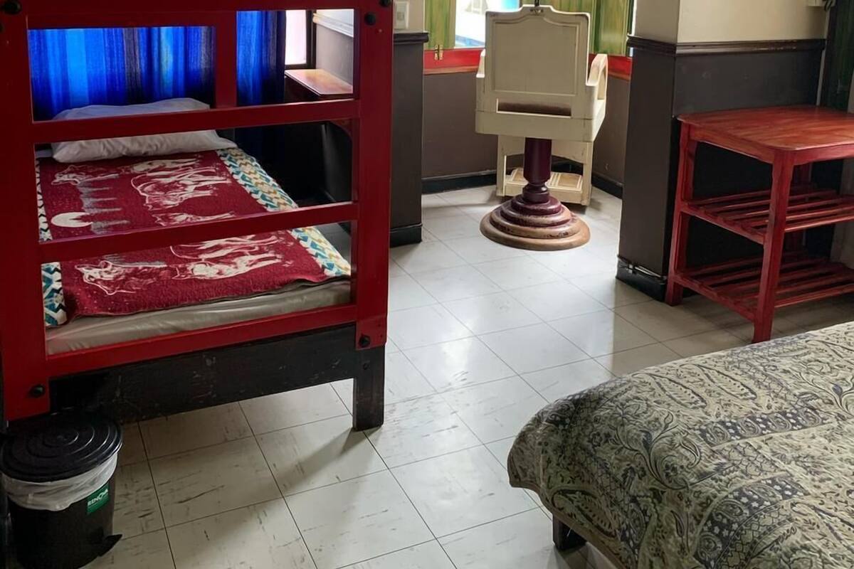 A room with bunk beds, a desk, a chair, and a television.