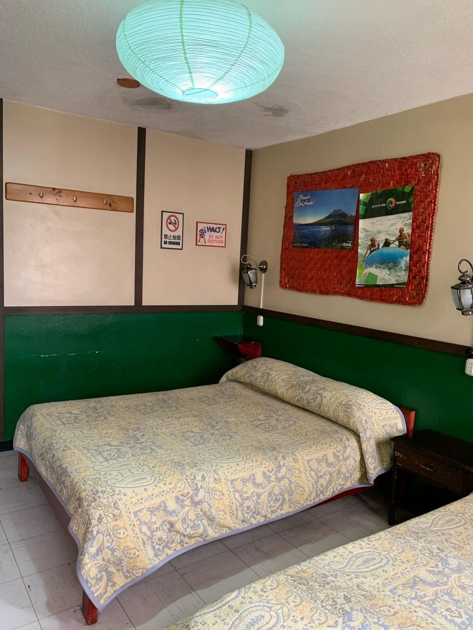 Una habitación con una cama, pared verde, un cartel y un ventilador de techo.