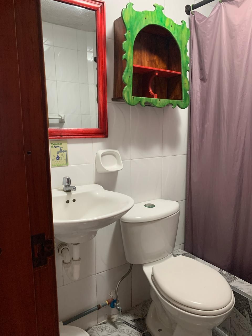 A bathroom with a white sink, a toilet, and a mirror with a red frame.