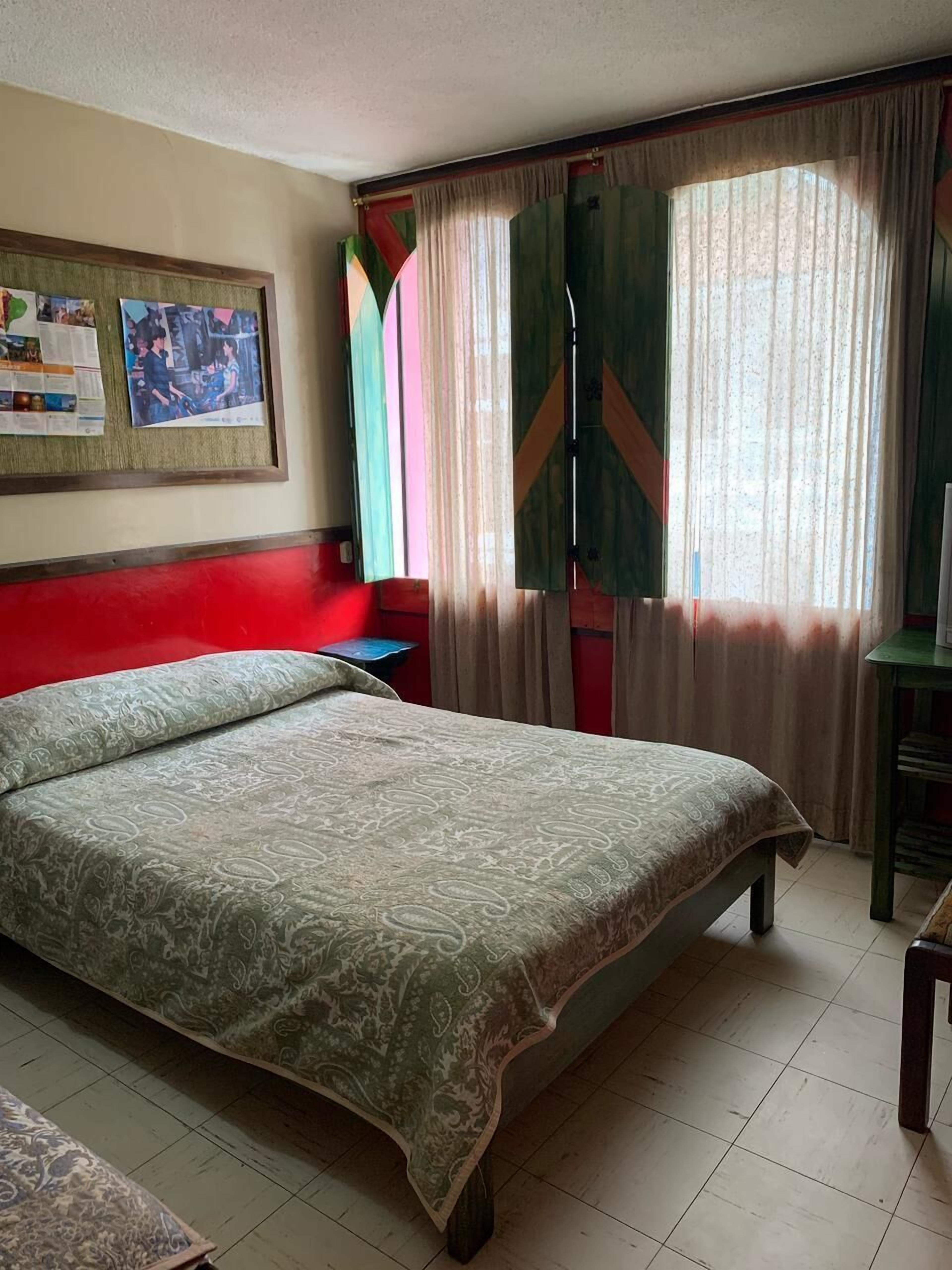 Una habitación de hotel con una cama grande, un escritorio, una silla y un tablón de anuncios en la pared.