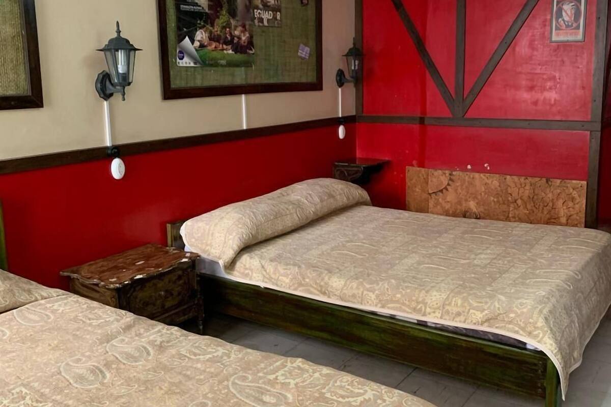 A hotel room with two beds, a red accent wall, and a ceiling light fixture.