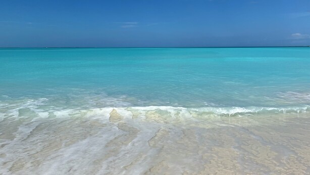 A beach with clear turquoise water and a sandy shore. - Treasure Cay Beach Villa Magic (Treasure Cay)