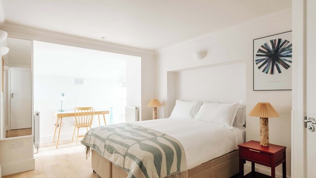 A bedroom with a bed, bedside table, lamp, and a chair. - The Regency: Cozy 1 BR retreat in Victoria  (LG) (London)