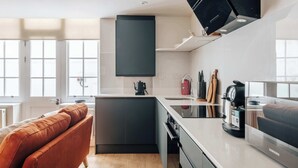 A modern kitchen with a central island, dark cabinetry, and a Samsung refrigerator. - The Regency: Cozy 1 BR retreat in Victoria  (LG) (London)