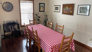 A dining area with a checkered tablecloth, wooden chairs, a clock, and framed artwork on the wall. - Charming cul-de-sac 5BR 3.5BA in State College, PA (Port Matilda)