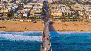 A pier extending into the ocean with a white building at the end. - Coastal Charm Awaits: Book Your Getaway Today! (Manhattan Beach)