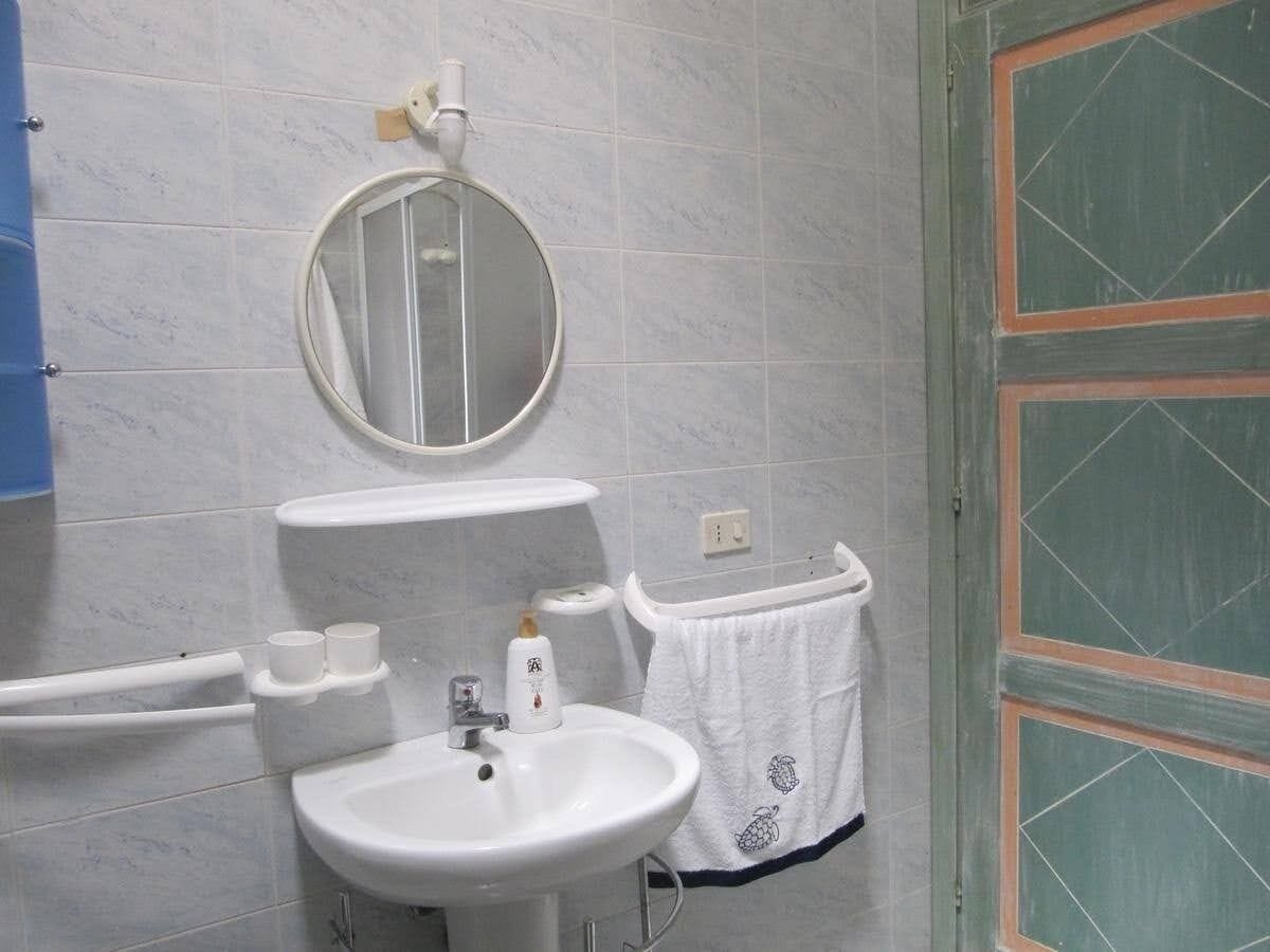 Ein Badezimmer mit einem weißen Waschbecken, einem Spiegel und einem Handtuchhalter.