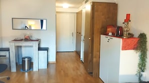 Cozy retreat with a kitchenette, wooden wardrobe, and potted plant.