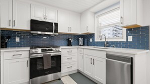 A modern kitchen with white cabinets, a stainless steel stove, and a dishwasher. - Cozy Condo in Siesta key with boat dock (Sarasota)