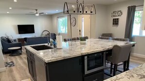 A modern kitchen with a large island, black cabinetry, and stainless steel appliances. - Modern Oasis in the Desert (Tempe)