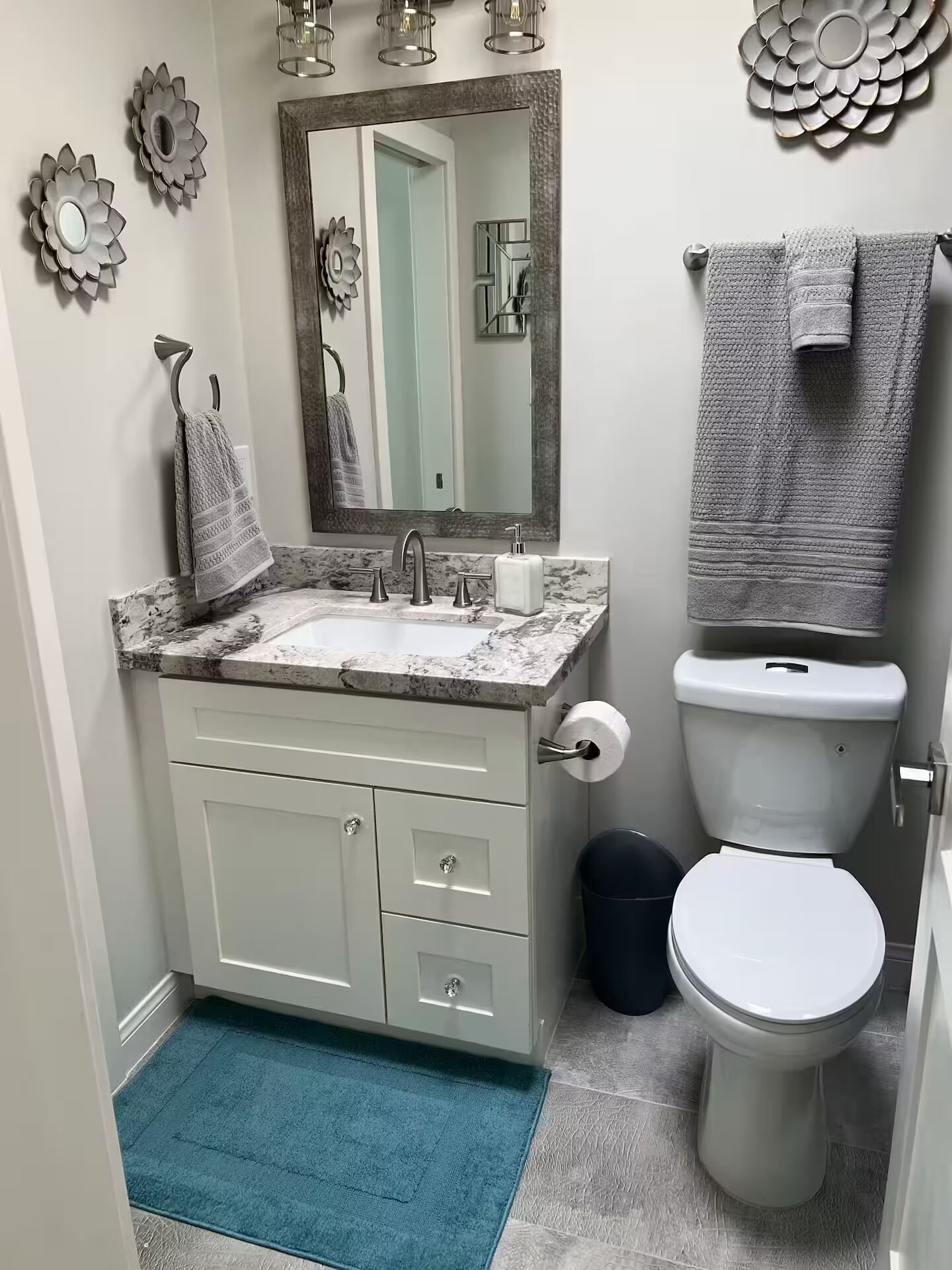 Een badkamer met een marmeren wastafel, toilet en een blauw vloerkleed.