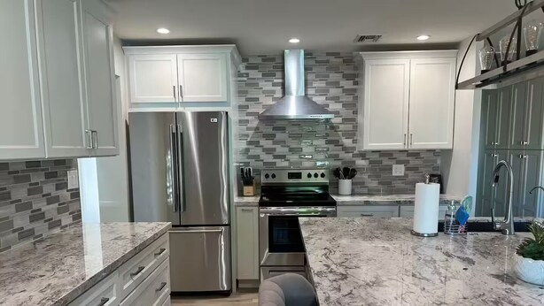 A modern kitchen with stainless steel appliances, white cabinets, and a marble countertop. - Modern Oasis in the Desert (Tempe)