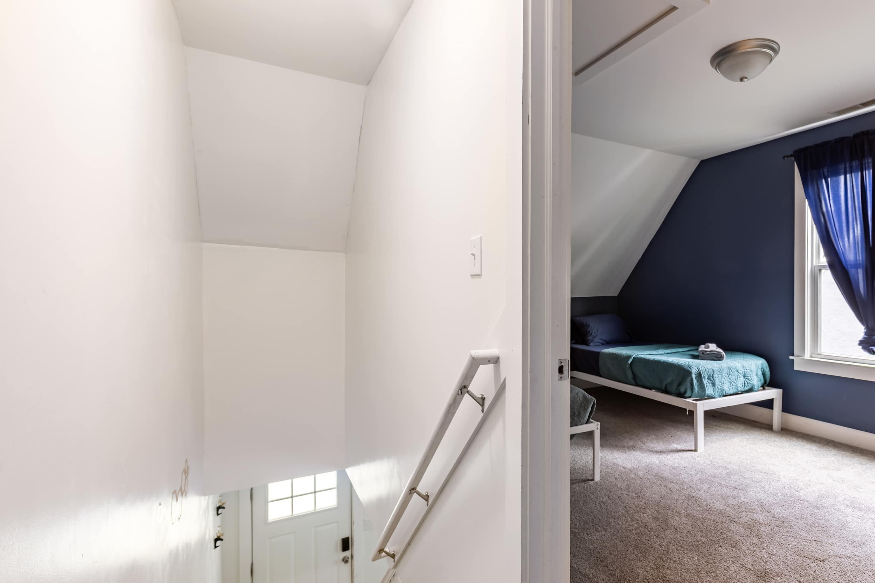 A room with a bunk bed, a window with blue curtains, and a white ceiling.