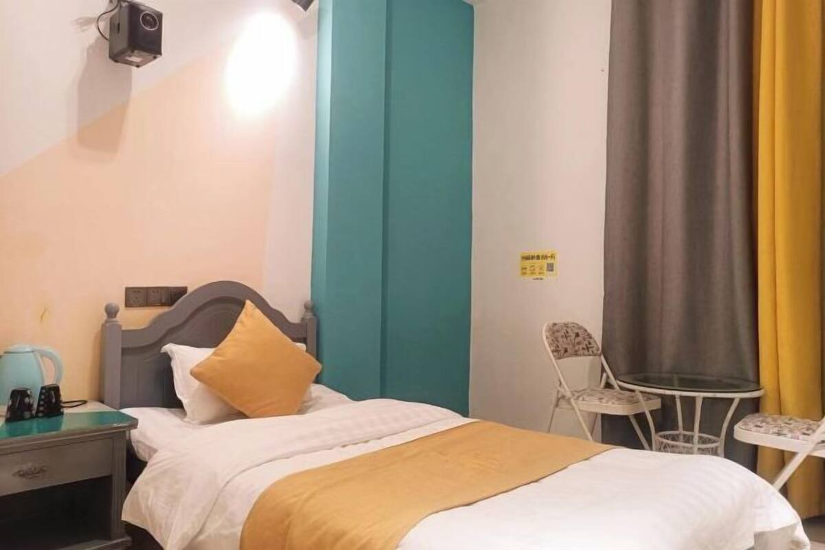 A hotel room with a bed, a nightstand, a chair, and a small table.