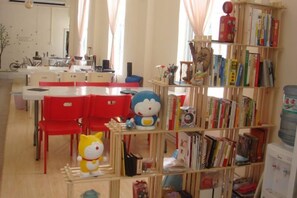 Une pièce avec une chaise rouge, une bibliothèque et une table.
