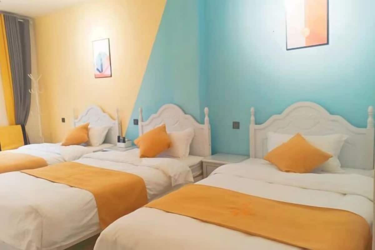 A hotel room with two beds, each with white headboards and orange bedding.