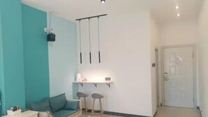 A room with a bed, a teal-colored sofa, two stools, a small table with a shelf, and a door. - Beihai Hai Yi Hurried That year Inn (Second inn) (Beihai)
