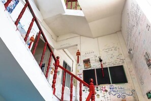 A staircase with red balusters leading to a landing with a blackboard and various writings.