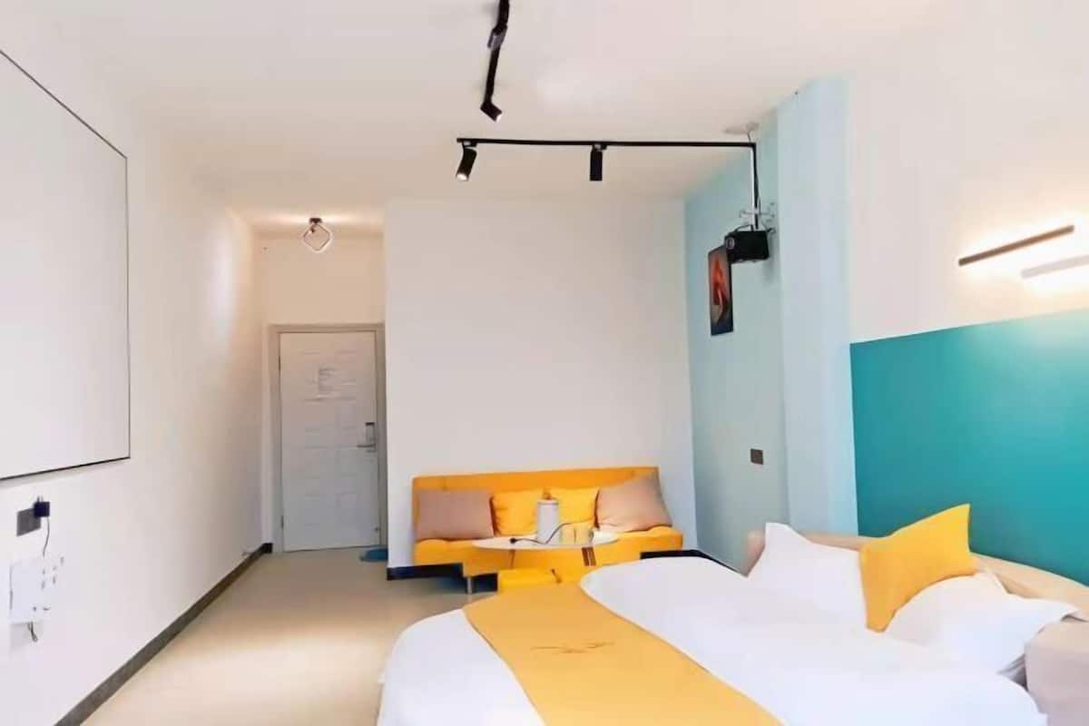 A modern hotel room with a bed, a sofa, and a desk.