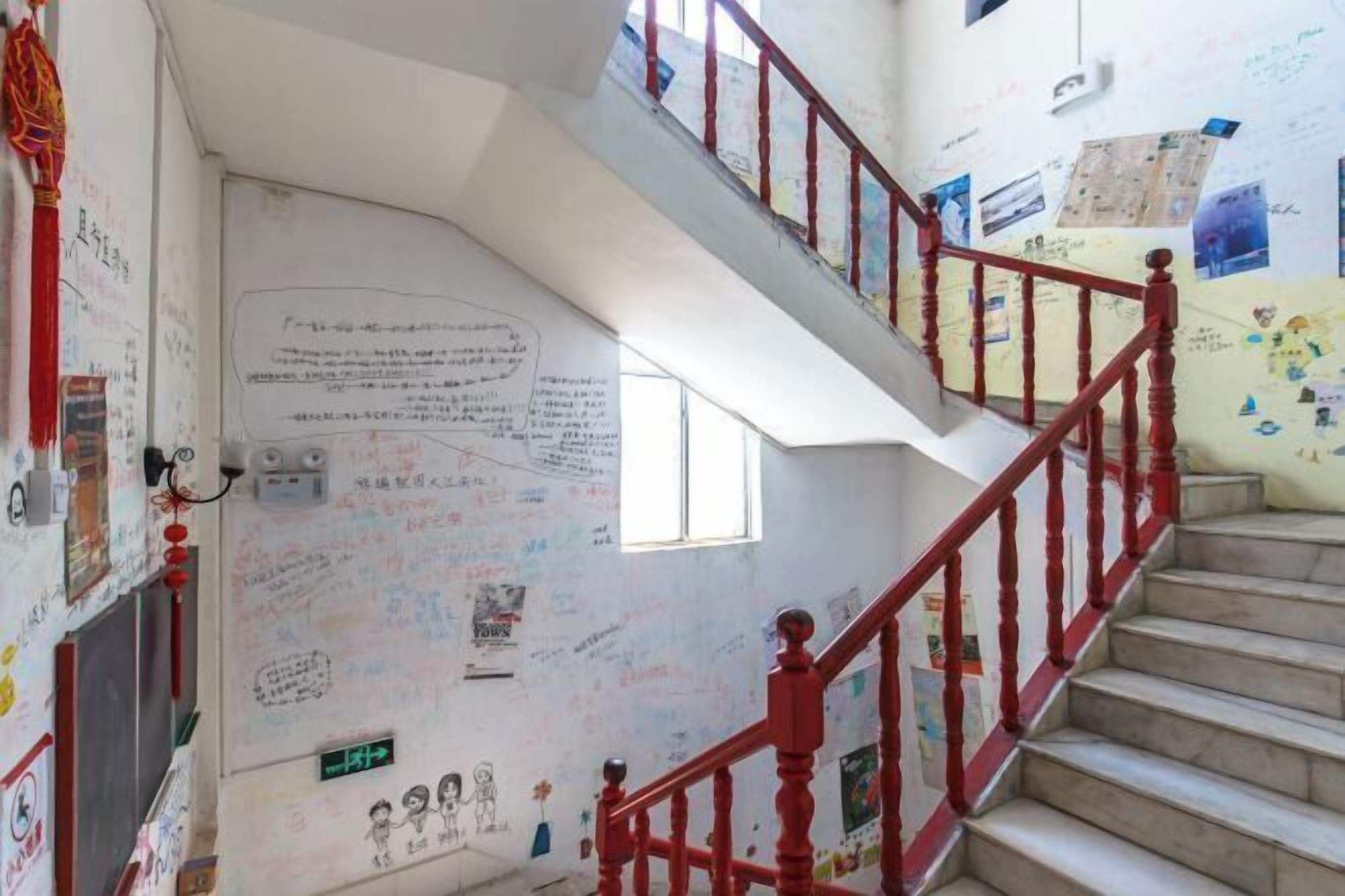 A staircase with red railings and walls covered in various writings and drawings.