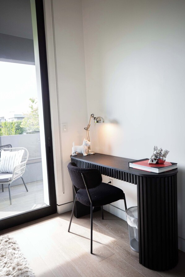 A modern room with a desk, a chair, a lamp, and a small statue on the desk. - Melrose Mansion - Pool, Rooftop + Firepit & Grill (West Hollywood)