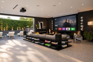A modern living room with a large flat-screen TV, a sofa, a coffee table with books, and a small side table.