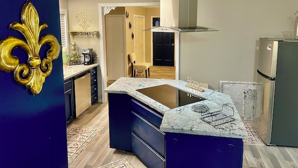 Una cocina moderna con una pared de acento azul oscuro, una encimera de mármol y un refrigerador de acero inoxidable.