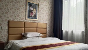A hotel room with a large bed, a headboard, floral wallpaper, a framed picture, and a window with curtains. - Shell Hotel (Shanghai Pujiang Town Zhuyuan Road) (Shanghai)