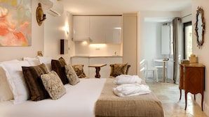 Een hotelkamer met een groot bed, een tafeltje, een stoel en een kitchenette.