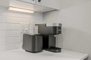 Une cuisine moderne dotée d’une machine à café intégrée et d’un grille-pain, le tout posé sur un plan de travail blanc.