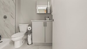 Un baño moderno con inodoro, un armario y zona de ducha.