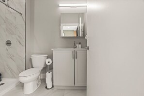 A modern bathroom with a toilet, a cabinet, and a shower area. - Luxury 1BD | 3 Beds | Northern Liberties (Philadelphia)
