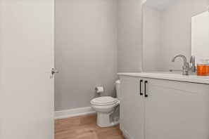 Een badkamer met een toilet, een wastafel met spiegel en een kast.