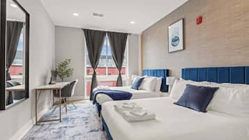 A hotel room with two beds, a desk, and a view of the city.