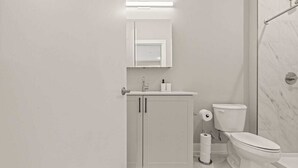 A modern bathroom with a toilet, sink, and shower area.