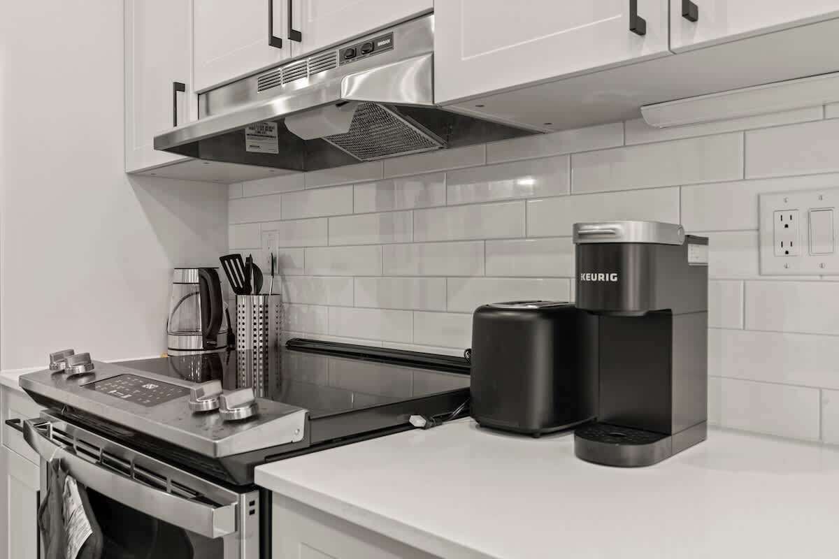 A modern kitchen with a built-in stove, a coffee maker, and a kettle.