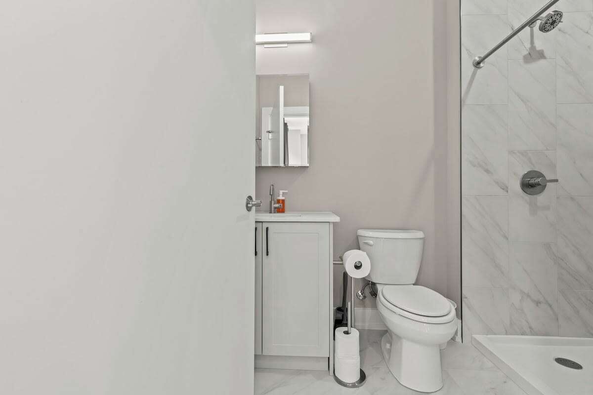 Een moderne badkamer met toilet, wastafel en douche.