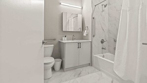A modern bathroom with a toilet, sink, vanity, and a walk-in shower.